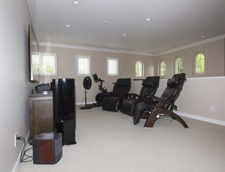 Family room with a sitting area, workout equipment and a ponywall with white wood baseboards and cap