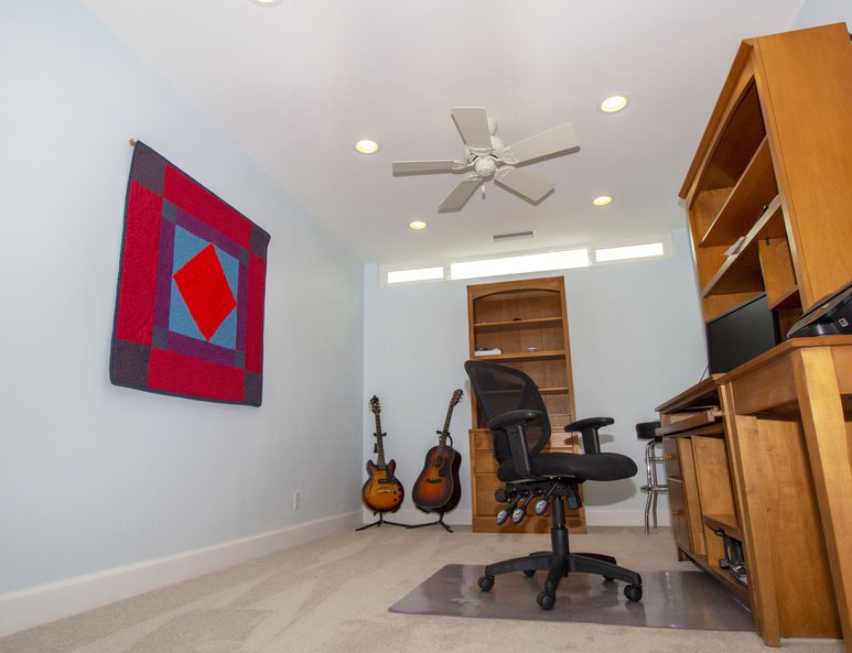 Open loft being utilized as a home office with a ceiling fan and recessed lighting.