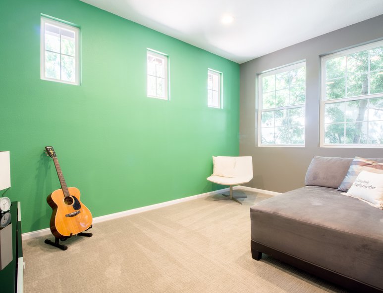 Open loft family room with lime green accent wall and ample lighting.