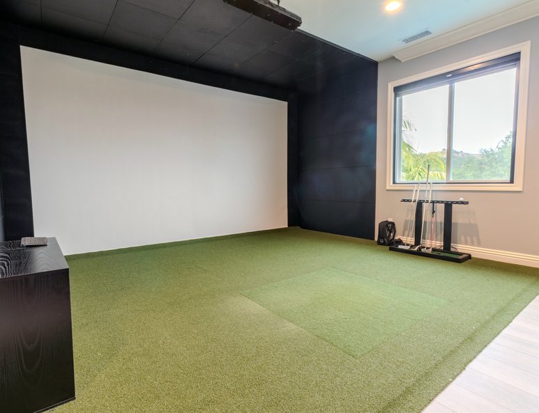 Home theater after renovation with a large projection screen, green flooring, gray walls, and tall windows providing natural light.