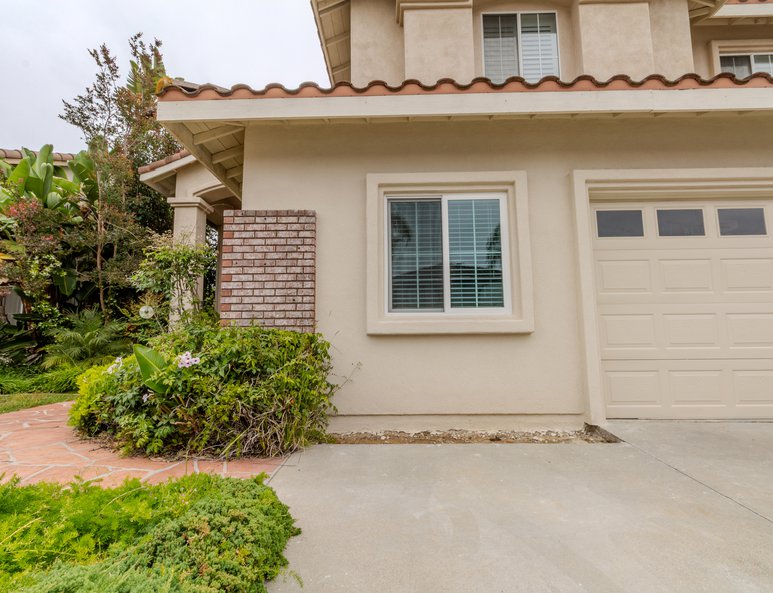 Front exterior after renovation with replacement windows, updated stucco finishes, driveway, and landscaped front yard.