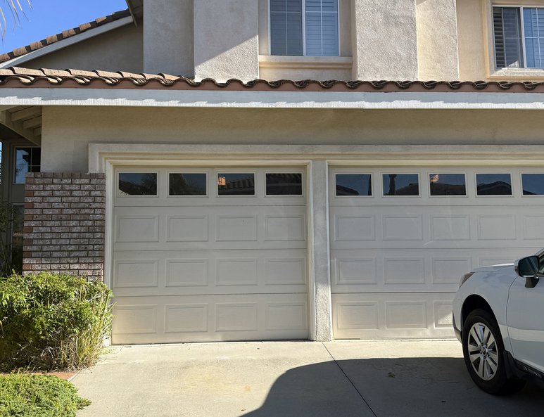 Front exterior before renovation with original windows, stucco façade, attached garage, and driveway leading to the street.