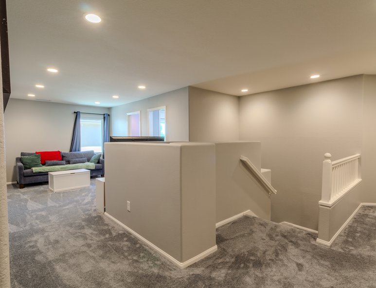 Loft hallway after renovation with gray carpet, white half wall, recessed lighting, and open overlook into adjoining spaces.