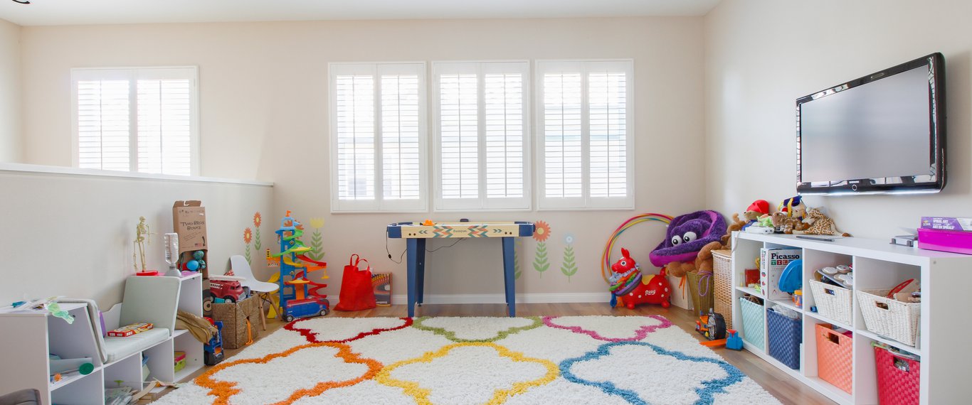 Open loft playroom with colorful rug, ponywall and multiple toys