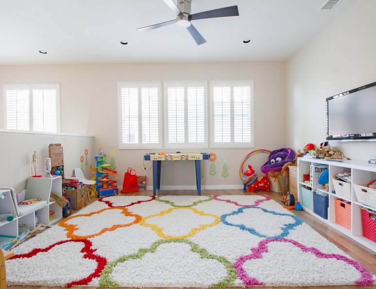 Open loft playroom with colorful rug, ponywall and multiple toys