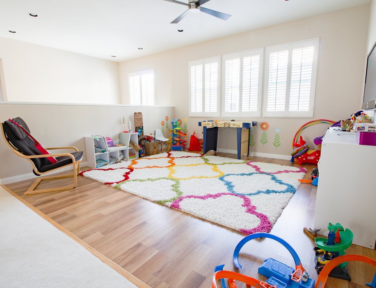 Open loft playroom with colorful rug, ponywall and multiple toys