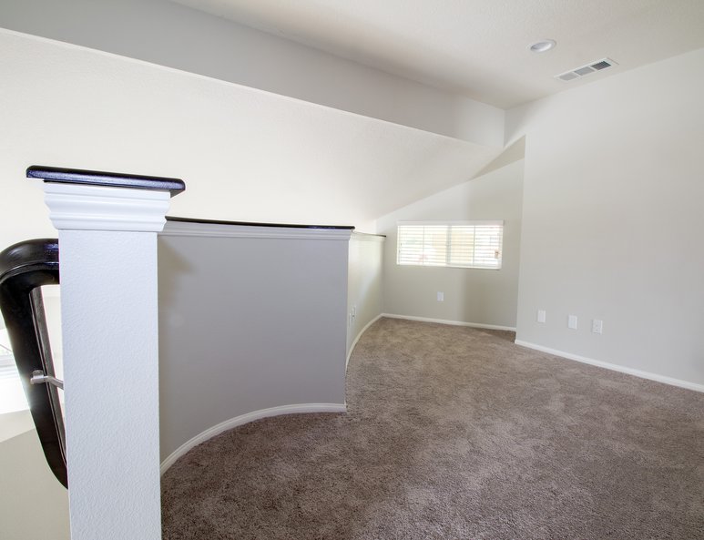 Curved ponywall in open loft with white wood baseboards and and dark wood cap