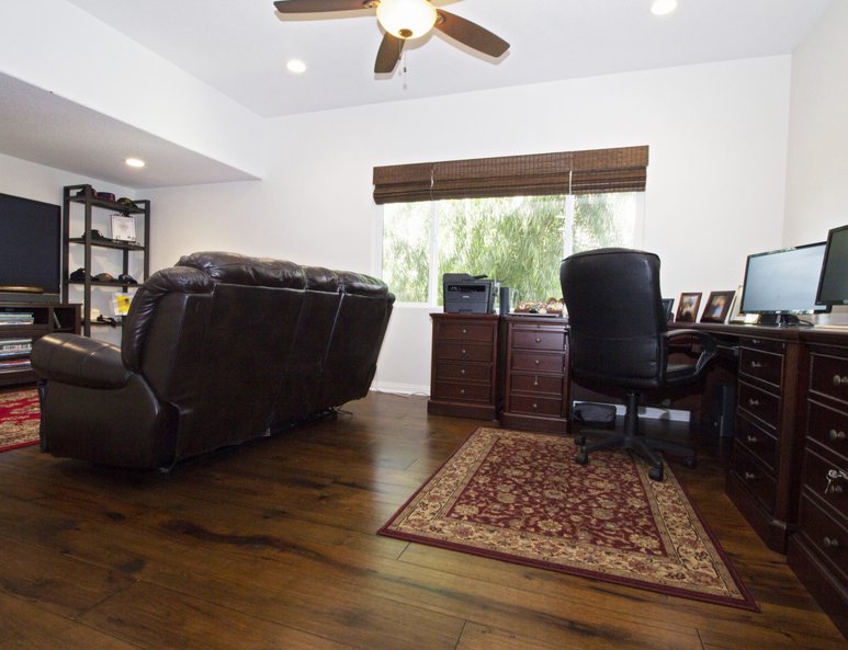 Open loft used as a family room and home office space with recessed lighting and ceiling fan.