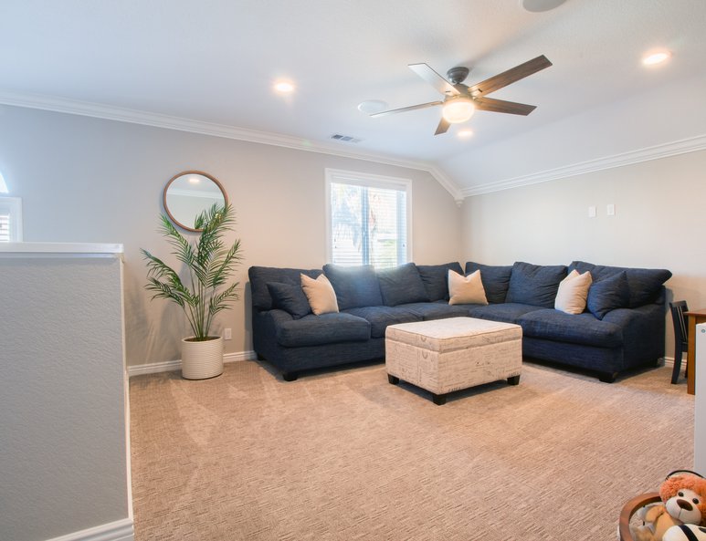 Sectional in newly added open loft with recessed lighting and a ceiling fan.